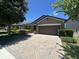 Single-story home showcases a brown exterior, a two-car garage, a brick paver driveway and manicured landscaping at 2436 Gratia Pl, Casselberry, FL 32707