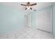 This bedroom features white tile floors, a ceiling fan, and a closet with louvered doors at 2637 Debany Rd, Kissimmee, FL 34744