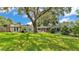 Expansive backyard with mature trees, a spacious lawn, a screened-in lanai, and a cozy pergola at 2727 Easton Ter, Lakeland, FL 33803