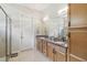 Well-lit bathroom with double sinks, granite countertops, and a glass-enclosed shower at 2772 Southland St, St Cloud, FL 34772