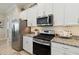 Modern kitchen with stainless steel appliances, granite countertops, and white cabinets at 2772 Southland St, St Cloud, FL 34772