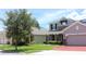 Street view of a two-story home with a three car garage, stone accents, and a well-manicured lawn at 2805 Carter Grove Ln, Kissimmee, FL 34741