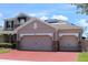 Three car garage with red brick driveway, stone accents, solar panels, and taupe paint at 2805 Carter Grove Ln, Kissimmee, FL 34741