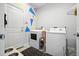 Bright laundry room with whimsical triangle wall art, washer, dryer, and storage at 3390 George Sauls St, Deltona, FL 32738