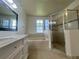 Bright bathroom featuring a soaking tub, walk-in shower, and vanity with marble countertop at 343 Marquee Dr, Kissimmee, FL 34758