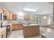 Well-lit kitchen features wood cabinets, center island, stainless appliances, and adjacent living area at 364 Fish Hawk Dr, Winter Haven, FL 33884