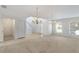 Bright living room featuring neutral carpet, tiled entry, chandelier, and large windows for natural light at 364 Fish Hawk Dr, Winter Haven, FL 33884