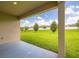 Covered patio overlooking a large backyard with green grass and mature trees at 371 Pinecrest Loop, Davenport, FL 33837