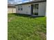 Lush green backyard with a well-maintained lawn, sliding glass door, and partial fencing at 3839 Marbella Way, Davenport, FL 33897
