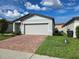 Single-story house with a brick driveway and well-kept lawn on a sunny day at 3839 Marbella Way, Davenport, FL 33897