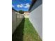 Narrow side yard featuring green grass and a privacy fence under a bright, sunny sky at 3839 Marbella Way, Davenport, FL 33897