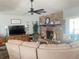Cozy living room featuring a stone fireplace, ceiling fan, and comfortable seating for relaxing and entertaining at 421 Bridle Path, Casselberry, FL 32707