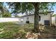 View of the house exterior, patio, and fenced-in yard shaded by a large tree, offering privacy and comfort at 447 Hammerstone Ave, Haines City, FL 33844