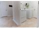 Well-lit laundry room featuring a white washer and dryer, tile flooring and shelving for storage at 4928 Cortland Dr, Davenport, FL 33837