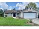 Charming one-story home features a well-maintained front yard, a two-car garage, and solar panels on roof at 5230 Clarion Oaks Dr, Orlando, FL 32808