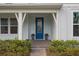 Inviting front porch with a vibrant blue door, complemented by potted plants and lush landscaping at 6522 Rover Way, St Cloud, FL 34771