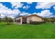 Expansive backyard featuring a sunroom, lush green lawn, and beautiful landscaping at 730 Villa Park Rd, Poinciana, FL 34759