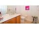 Bright bathroom featuring a wood vanity, framed mirror, decorative painting, and tiled flooring at 730 Villa Park Rd, Poinciana, FL 34759