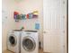 Functional laundry room with front loading washer and dryer, tile flooring, and storage shelf at 730 Villa Park Rd, Poinciana, FL 34759