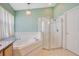 Main bathroom featuring a luxurious soaking tub, glass shower, and neutral tile flooring at 746 Stonewyk Way, Kissimmee, FL 34744