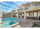Enclosed outdoor pool and spa area with covered patio, dining table, and lounge seating at 9126 Sommerset Hills Dr, Davenport, FL 33896