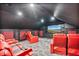 Modern theater room features red leather reclining chairs and large television for an immersive cinematic experience at 9905 Lanai View Ct, Windermere, FL 34786