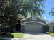 Inviting one-story home with a well-manicured lawn, mature tree, and covered entrance at 11039 Prairie Hawk Dr, Orlando, FL 32837