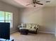 Cozy living room with a floral patterned sofa, rattan coffee table, ceiling fan, and a large window for natural light at 11039 Prairie Hawk Dr, Orlando, FL 32837