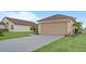 View of the home's two-car garage, spacious driveway, and tidy landscaping at 1197 E Grove Ave, Lake Wales, FL 33853