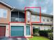 Charming condo featuring a teal garage door, screened balcony, and manicured landscaping at 12021 Villanova Dr # 111, Orlando, FL 32837