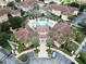 Aerial view of a community pool with palm trees, lounge chairs, and a clubhouse at 12021 Villanova Dr # 111, Orlando, FL 32837