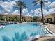 Inviting swimming pool with clear blue water, surrounded by lush landscaping, palm trees, and comfortable seating at 12021 Villanova Dr # 111, Orlando, FL 32837