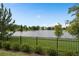 Scenic view of a tranquil lake from the property, bordered by lush greenery and a black metal fence at 14081 Gullstrand Ave, Orlando, FL 32827