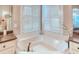 Bright bathroom featuring a large soaking tub under windows with plantation shutters and granite countertops at 142 Largo Dr, Poinciana, FL 34759