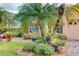 Home's exterior showcases lush palm trees, garden beds, and a brick-paved driveway, adding tropical charm at 142 Largo Dr, Poinciana, FL 34759