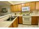 Cozy kitchen with wooden cabinets, white appliances and countertops, and stainless steel sink at 167 Scottsdale Sq # 167, Winter Park, FL 32792