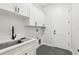 White laundry room with stainless steel sink, black matte faucet, and gray tile floor at 224 Valencia Ridge Dr, Auburndale, FL 33823