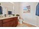 Bathroom featuring single sink vanity with warm wood cabinets, tiled floor, and wall decor at 256 Yellow Snapdragon Dr, Davenport, FL 33837
