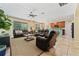 Open floor plan includes leather seating, ceiling fan, large windows, and view into the kitchen at 256 Yellow Snapdragon Dr, Davenport, FL 33837