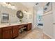 Spacious main bathroom featuring double sinks, warm wood cabinets, a large mirror, and tiled floors at 256 Yellow Snapdragon Dr, Davenport, FL 33837