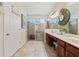 Spacious main bathroom featuring double sinks, warm wood cabinets, a large mirror, and walk-in shower at 256 Yellow Snapdragon Dr, Davenport, FL 33837