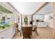 Bright dining area featuring a glass table, hardwood floors, wooden beams, and an open view of the lush backyard at 2571 Ames Haven Rd, Kissimmee, FL 34744