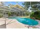 Screened-in pool area boasting a uniquely shaped pool, integrated spa, and verdant tropical plants at 2571 Ames Haven Rd, Kissimmee, FL 34744