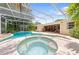 Beautiful screened-in pool and hot tub overlooking lush backyard and screened in patio seating area at 2571 Ames Haven Rd, Kissimmee, FL 34744