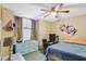 Cozy bedroom with a ceiling fan, blue dresser, and a window for natural light at 2626 Gentre St, Kissimmee, FL 34744