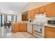 Open kitchen with white appliances and wooden cabinets, adjacent to a dining area with large windows at 2626 Gentre St, Kissimmee, FL 34744
