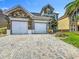 Two-story home with a stone facade, well-manicured lawn, and a three-car garage at 2669 Sand Hill Point Cir, Davenport, FL 33837
