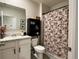 Well-lit bathroom features a vanity, toilet, cabinet, and floral shower curtain at 2727 Harmonia Hammock Rd, Harmony, FL 34773