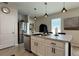 Open kitchen with an island, stainless steel appliances, white cabinets, and stylish pendant lights at 2727 Harmonia Hammock Rd, Harmony, FL 34773