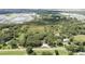 Aerial view of wooded lot with home nestled in the trees, nearby developments, and pond at 2810 Horton Rd, Kissimmee, FL 34744